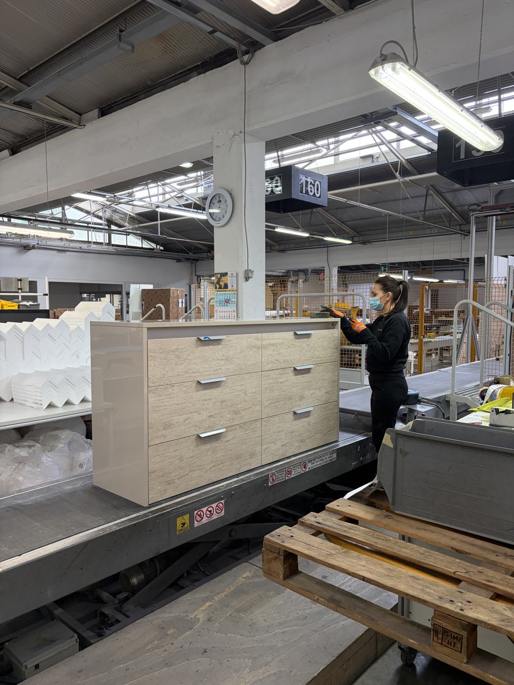 A worker checking a finished chest of drawers at the packing station
